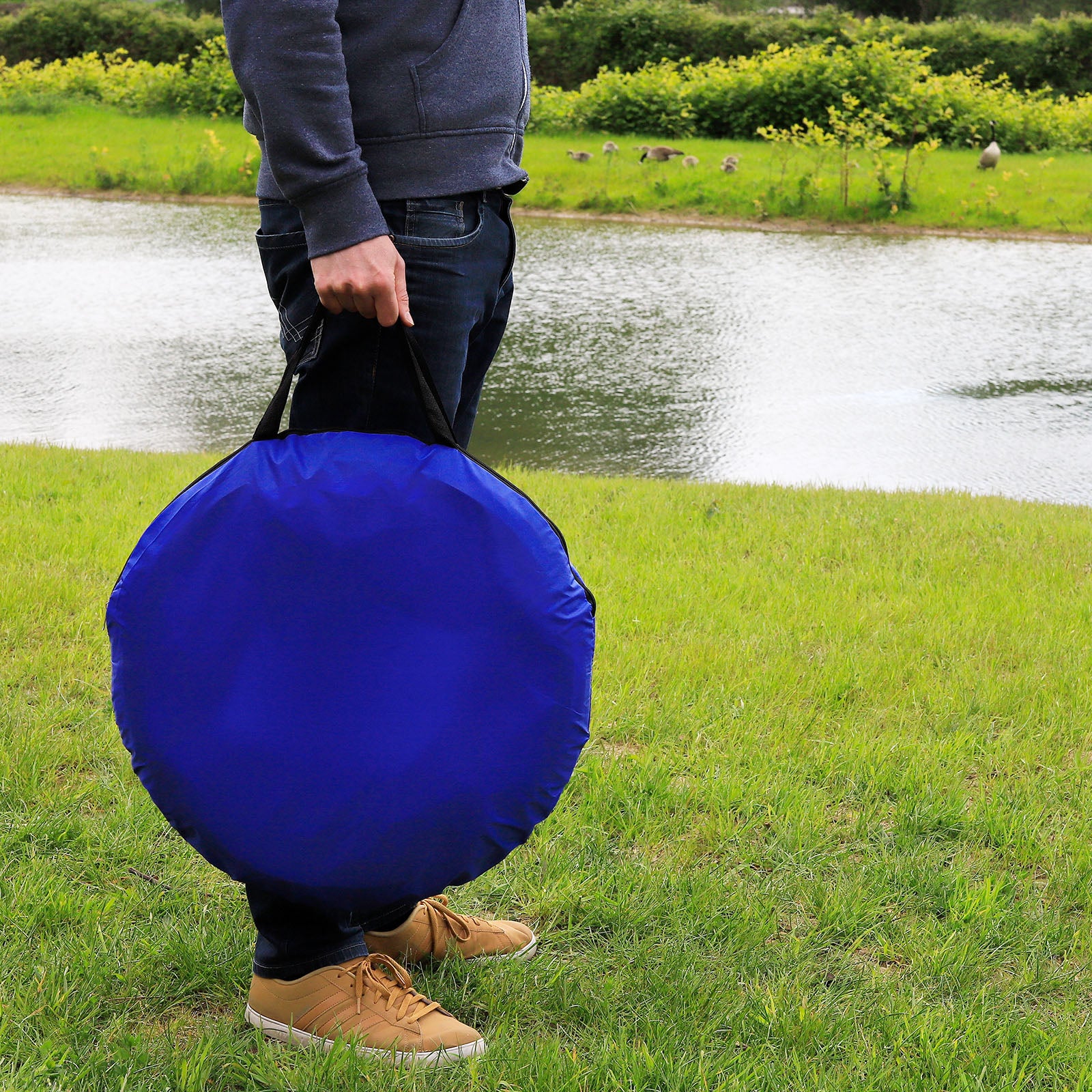 Mann trägt in Tragetasche eingepackten Tunnel auf Wiese